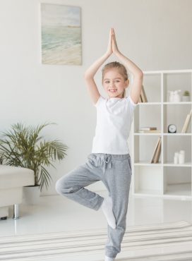 beautiful little child practicing yoga in tree pose